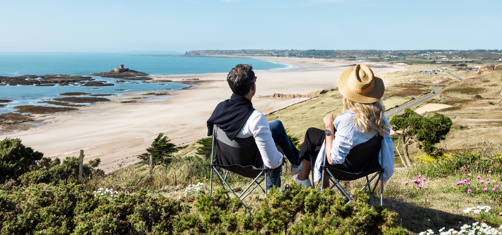 A couple sitting on the sand dunes over looking st ouens bay