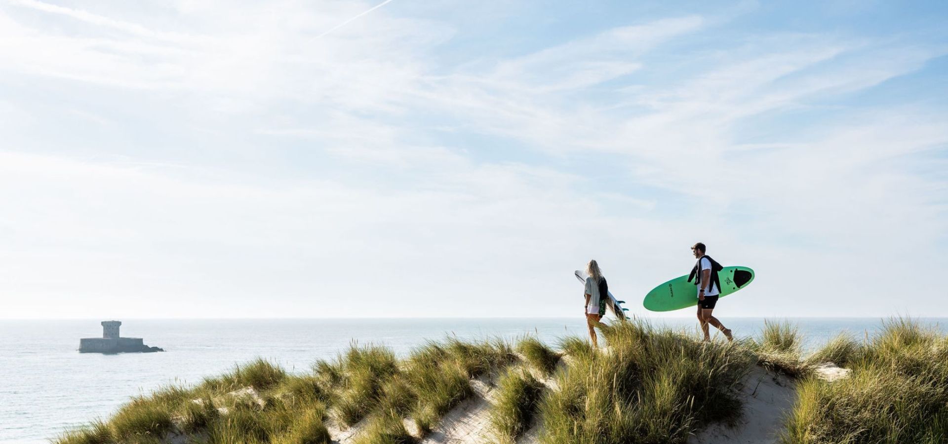 surfers walking through dunes to the sea