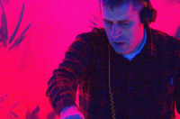 A DJ playing a set with a neon-red background.