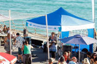 A tent on the St. Ouen's Bay promenade. There is a musician playing inside.