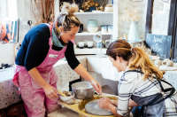 Ceramacist teaching someone how to use the wheel