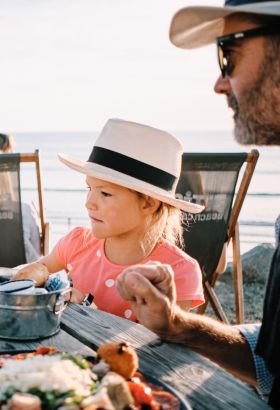 Couple with young child enjoying al fresco dining in the sun overlooking the sea