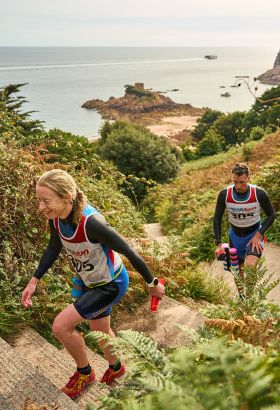 Man and a woman running on a coastal path wearing sportswear in Jersey