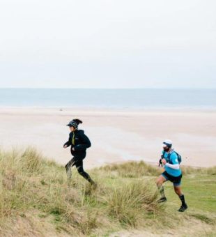 two people running along sand dunes at Le Braye