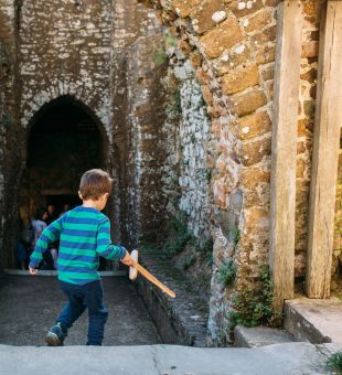 A child running through Mont Orgueil Castle with a wooden sword