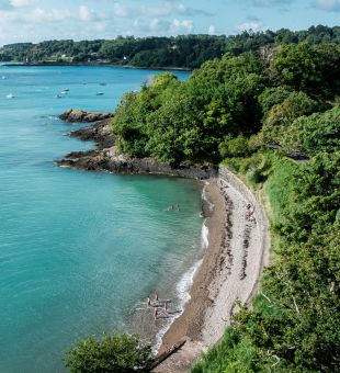 Aerial shot of swimmers entering the turquoise sea at Bel Val Bay in Jersey.