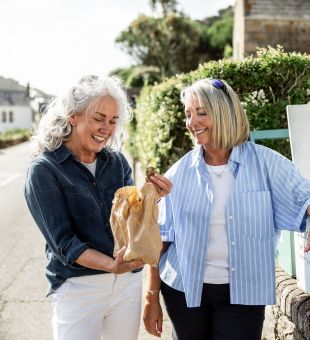 Two women at Jersey Royal Potato honesty box, eyeing up the produce.