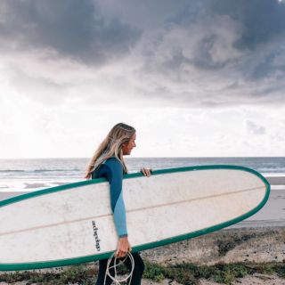 Rebecca walking to the surf with board