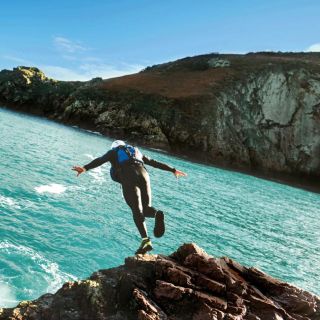person jumping off a cliff coasteering