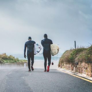 Two surfers walking along the slip at Le Braye