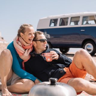 Couple drinking tea near their campervan on the slipway at the beach