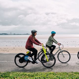Three women cycling e-bikes along the front in St. Helier Jersey Channel Islands