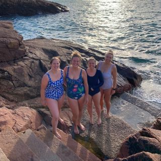 Four girls standing on rocks by the sea after a swim