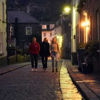 Group of friends walking along a cobbled street at night