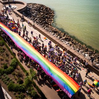 Pride rainbow banner held up by crowd.