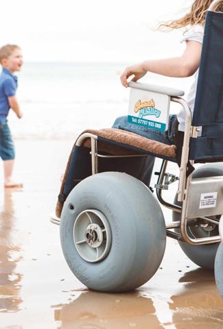 A little girl in a wheelchair on the beach