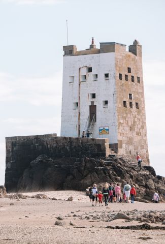 Seymour Tower at low tide with a group of people walking