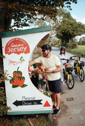 Couple picking up local produce from a roadside stall on bicycles