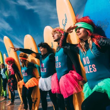 surfers holding surfboards dressed in 80s themed outfits