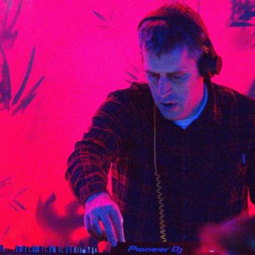 A DJ playing a set with a neon-red background.
