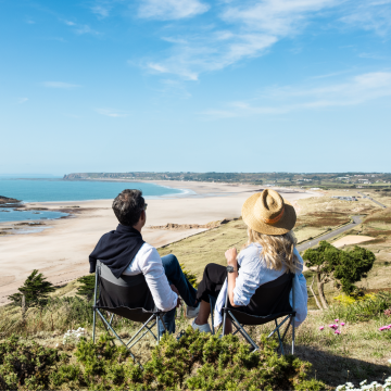 A couple sitting on the sand dunes over looking st ouens bay