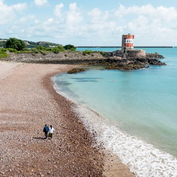 two people walking on a stony beach