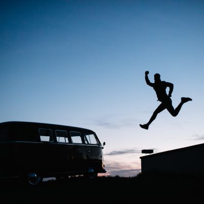 A man jumping from a wall next to a VW Combi campervan