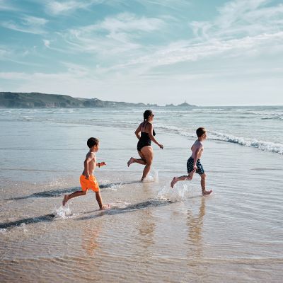 A family running into the sea on St. Ouen