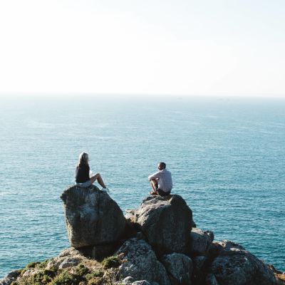 A couple sitting on a rock over looking the sea on the north coast cliffs
