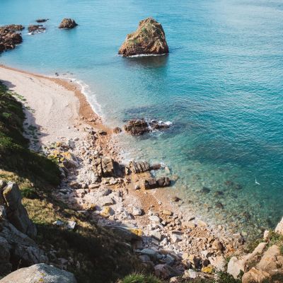 rocks surrounding pebble beach and turquoise sea