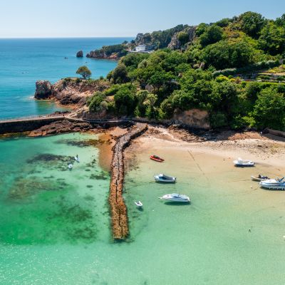 Aerial view of clear turquoise sea with boats moored in harbour at St. Brelade