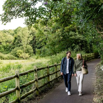 Couple walking through a leafy, tree-lined valley