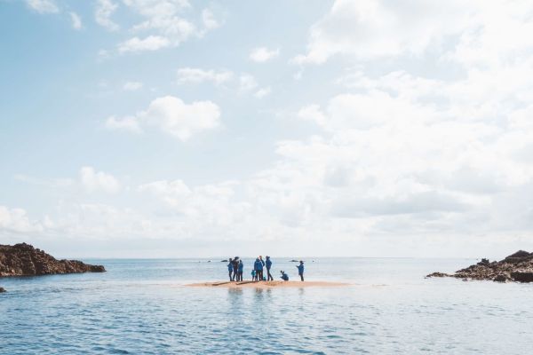 A group of people standing on a sandbank at Les Minquiers