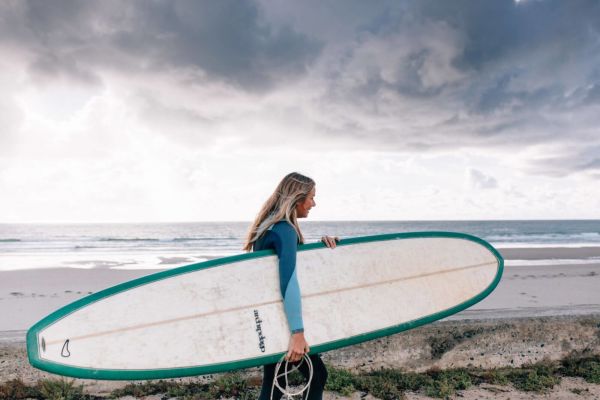 Rebecca walking to the surf with board