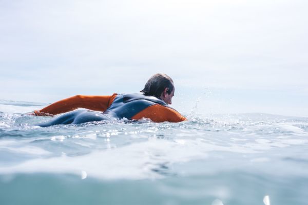 man paddling out to surf