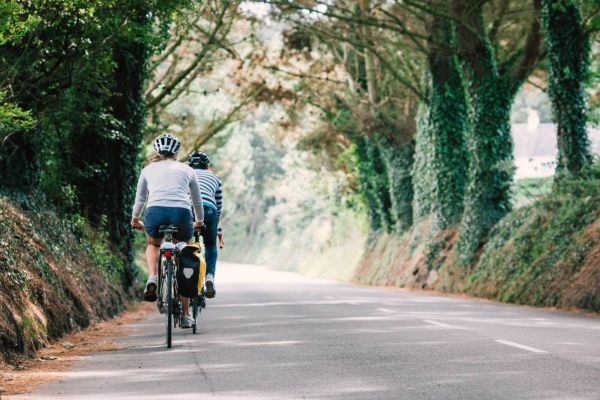 two cyclists cycling down a wooded lane