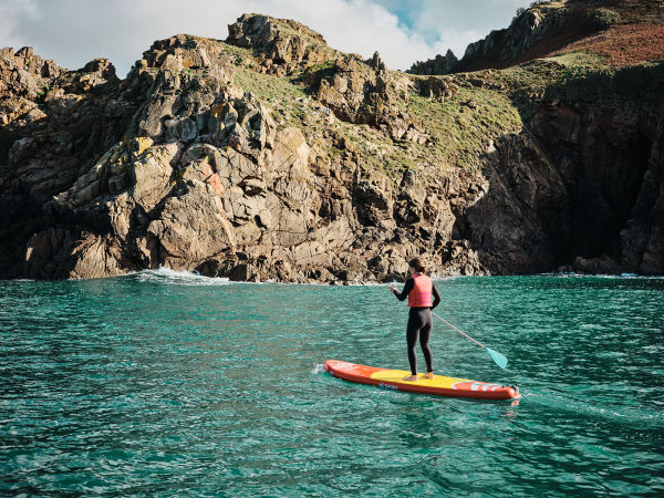 Woman paddling out near cliffs