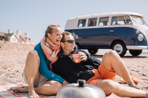 Couple drinking tea near their campervan on the slipway at the beach