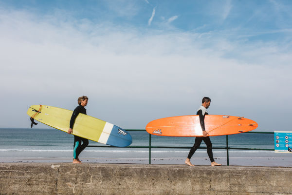 Two surfers carrying surf boards at St. Ouens Bay, Jersey