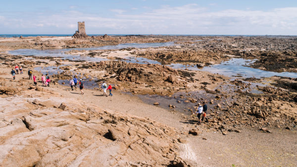 People walking on seabed at low tide towards Seymour Tower