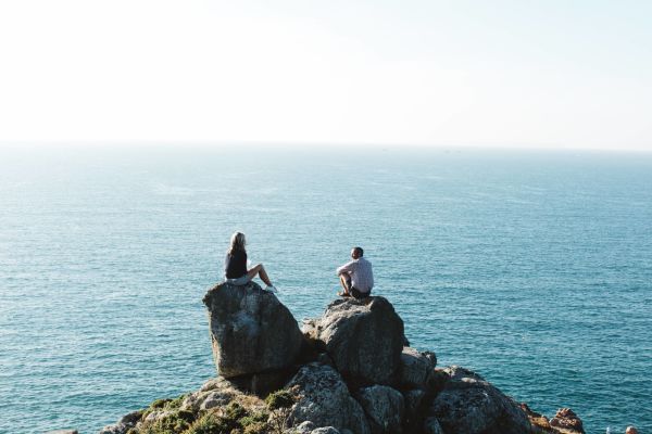 A couple sitting on a rock over looking the sea on the north coast cliffs