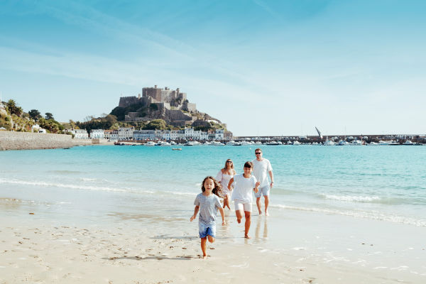A family on Grouville beach with Gorey Castle in the background