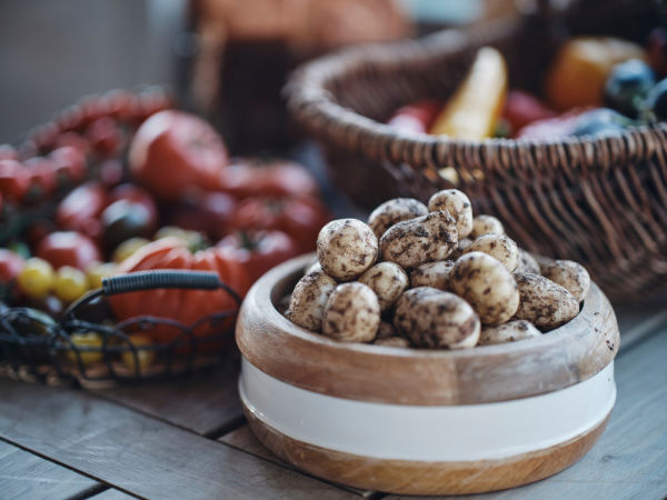 A bowl of Jersey Royal Potatoes on a table with other vegetables