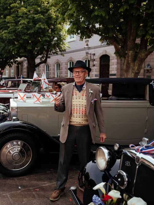 Older man with hat standing in front of a vintage car