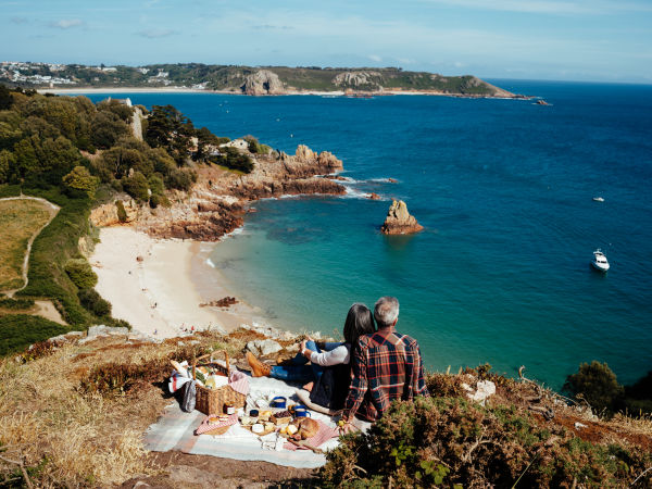 Couple enjoying a picnic on a high clifftop overlooking the sea