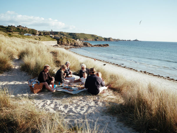 Family eating a picnic on sand dunes overlooking the sea