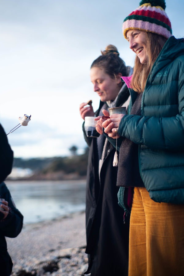 Women wrapped up warm on the beach enjoying hot drinks