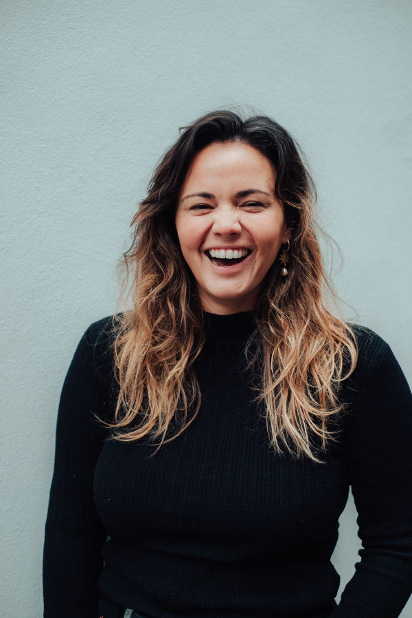 Headshot of a woman laughing in front of a blue background