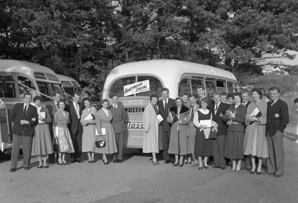 Group of couples standing in front of a vintage bus