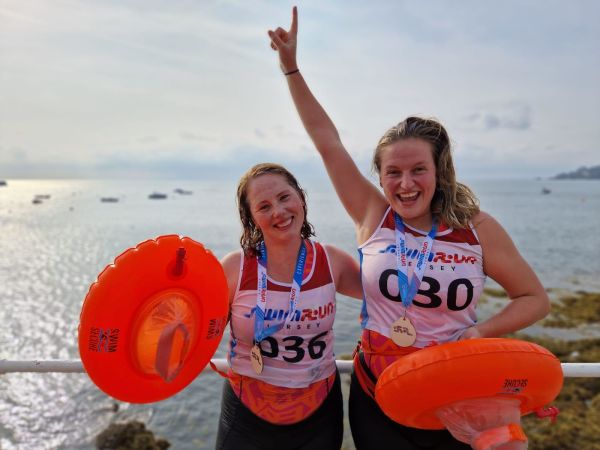 Two athletes with medals on posing for photo after completing swimrun challenge